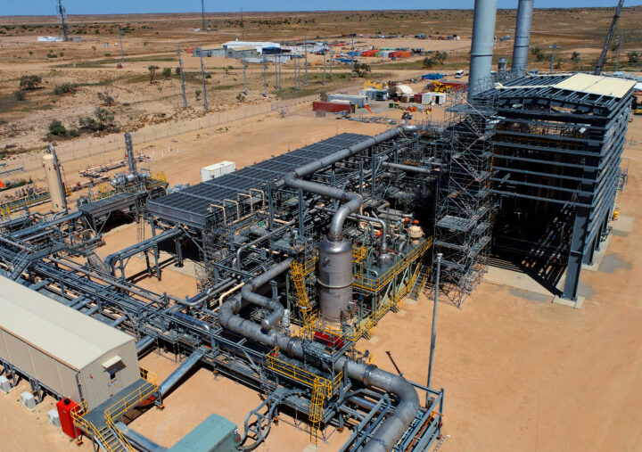 Aerial view of a gas plant surrounded by arid desert landscape, showcasing industrial structures and sparse vegetation.
